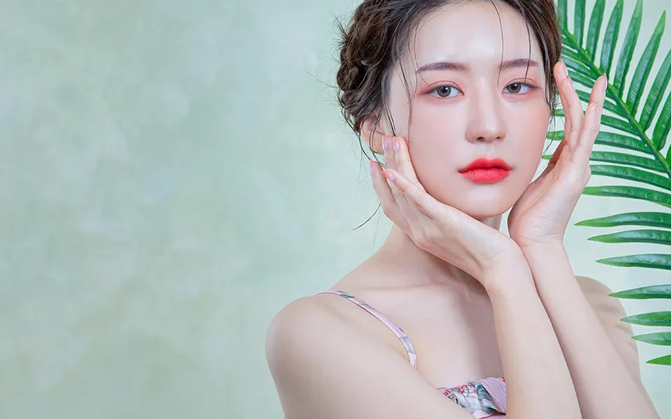 Model with clear, even-toned skin framing her face with her hands